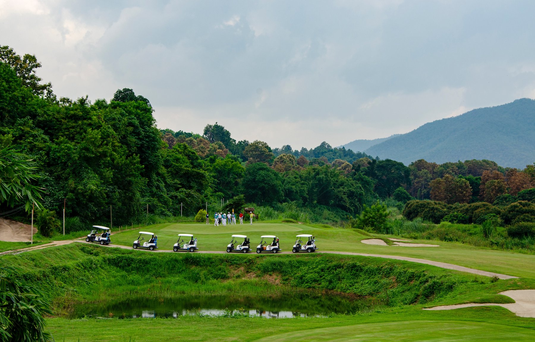 A golf green framed by trees and distant hills